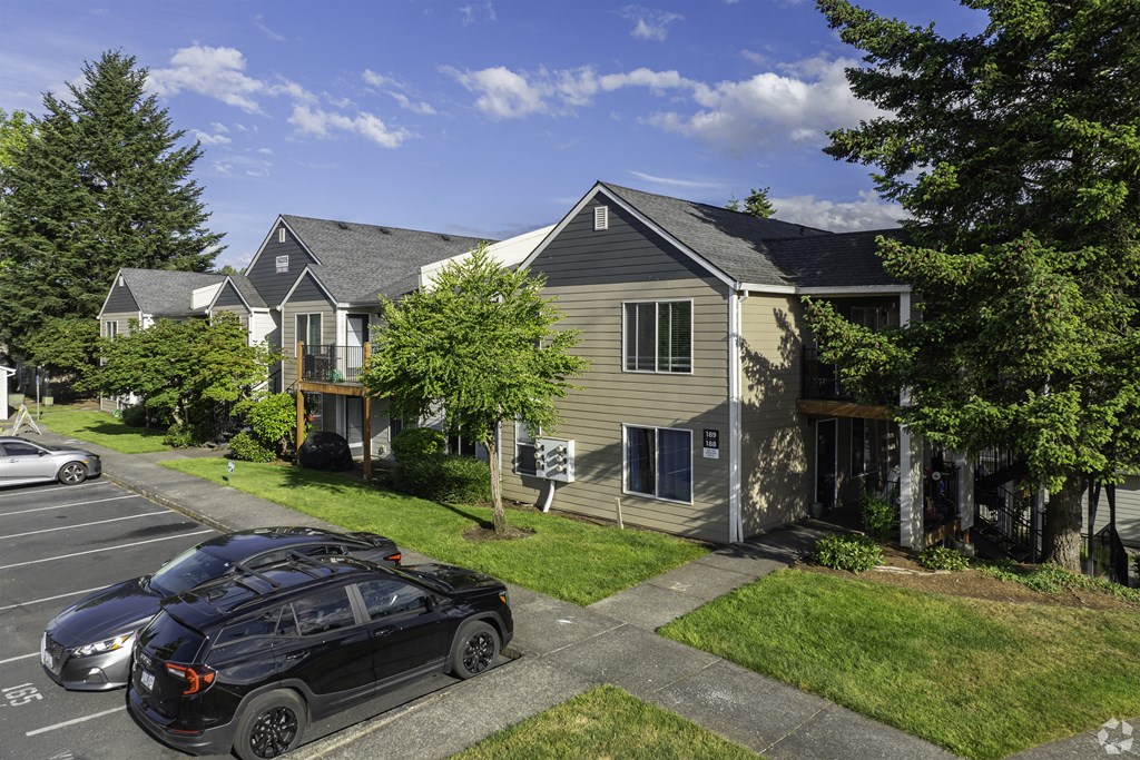 A black car is parked in a parking lot in front of a house.