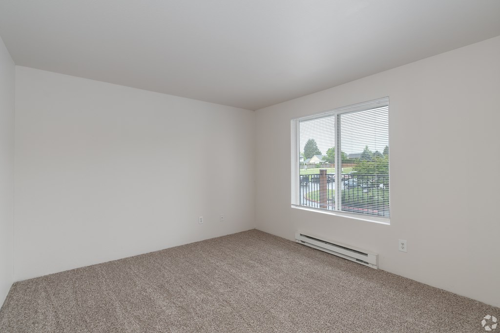 A room with a carpeted floor and a window with blinds.