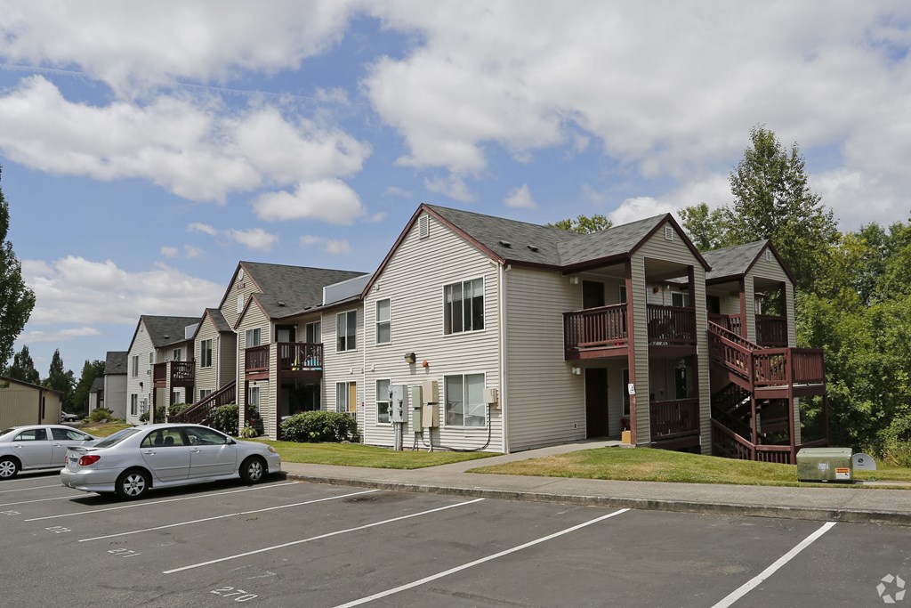 A parking lot with cars and apartment buildings in the background.