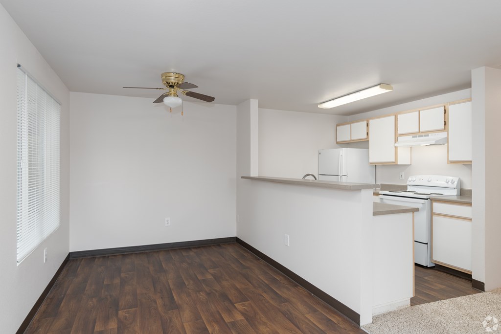 A room with a ceiling fan and a kitchenette.