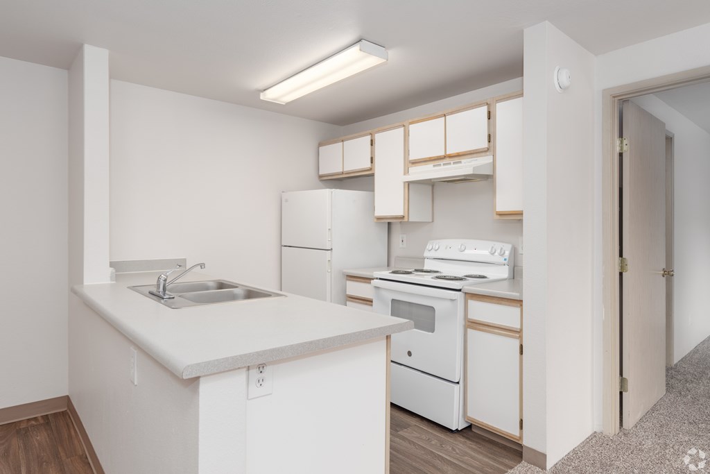 A white kitchen with a sink, stove, and oven.