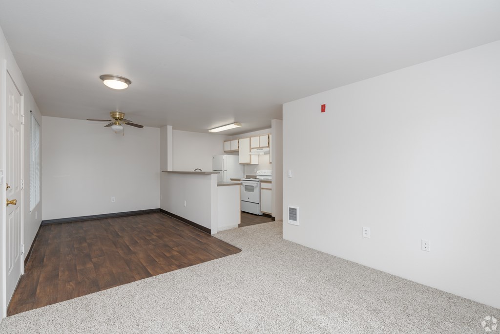A spacious room with a ceiling fan and a kitchenette in the corner.