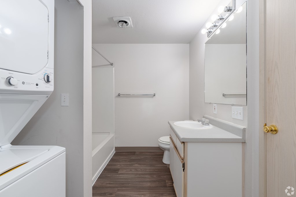 A small bathroom with a toilet, sink, and a washer and dryer.