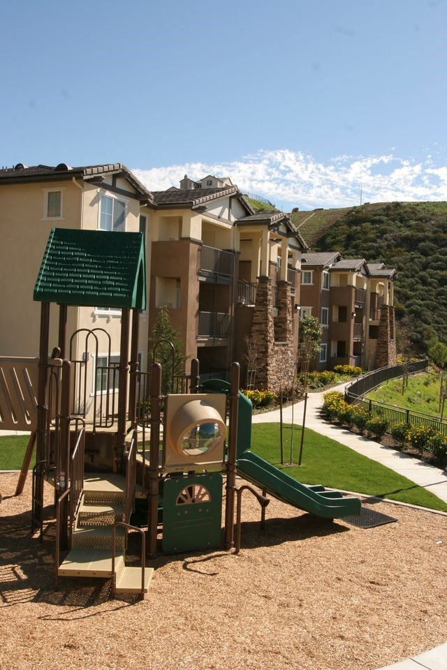 a playground with a slide in front of an apartment complex