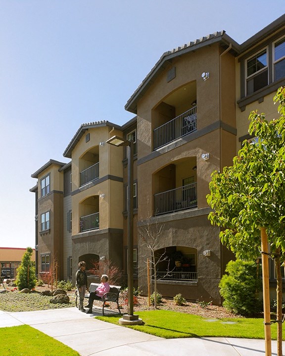a woman sitting on a bench in front of an apartment building