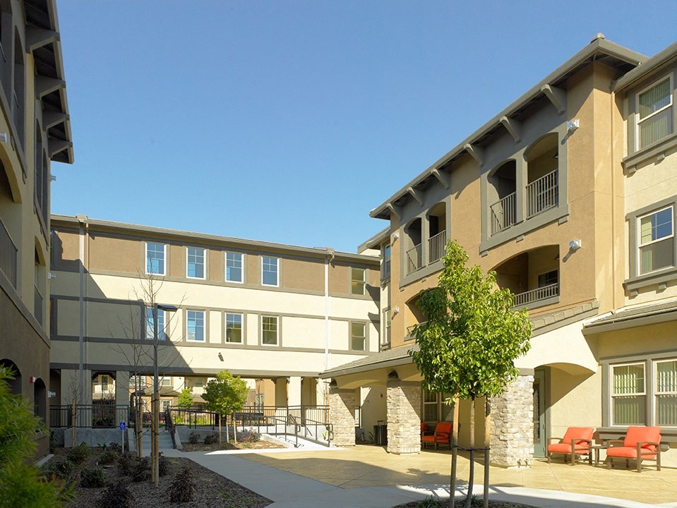 an exterior view of an apartment building with a patio and chairs