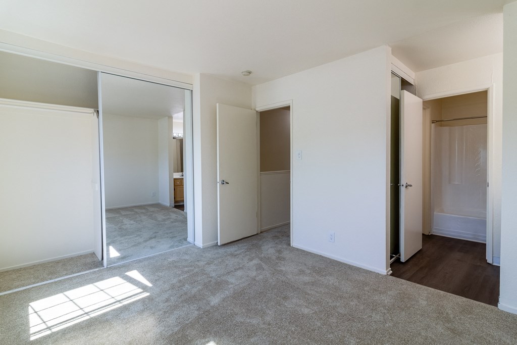 an empty living room with white walls and doors to different rooms