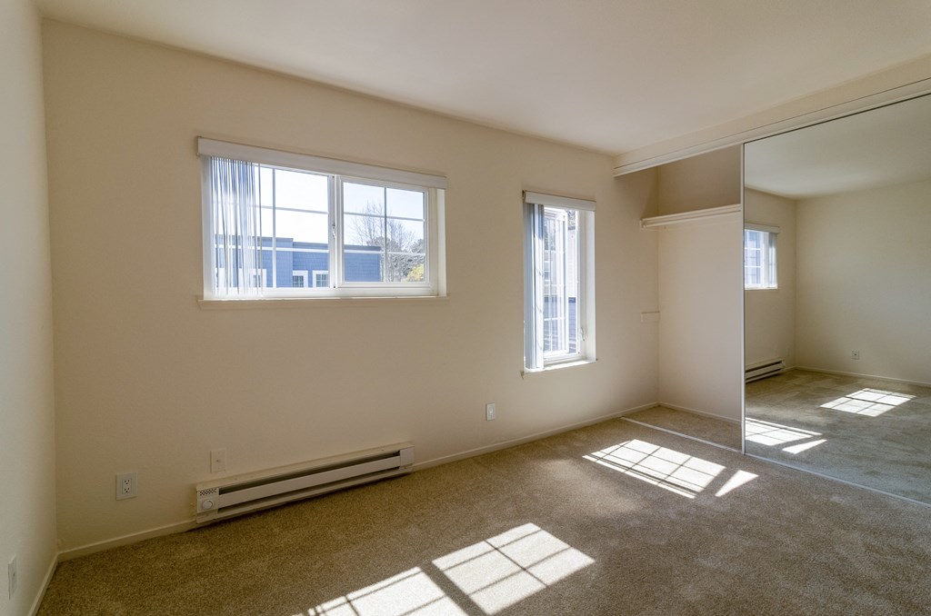 the living room of an empty home with sunlight coming through the windows