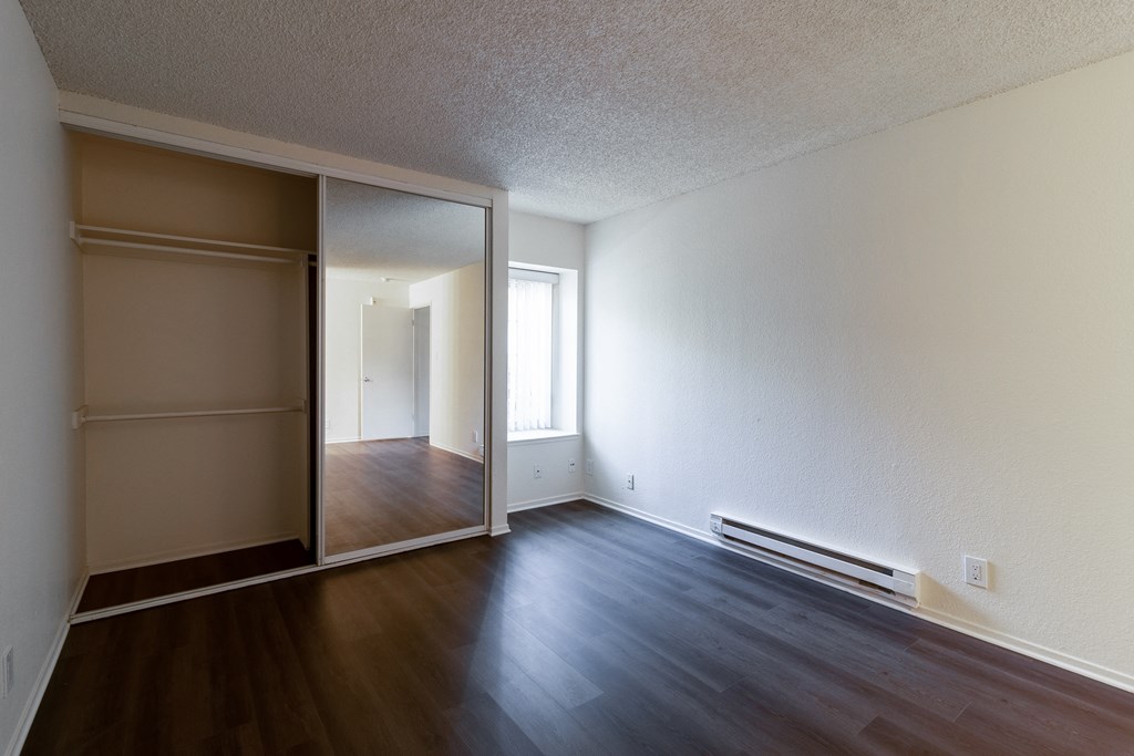 an empty living room with wood floors and a sliding glass door