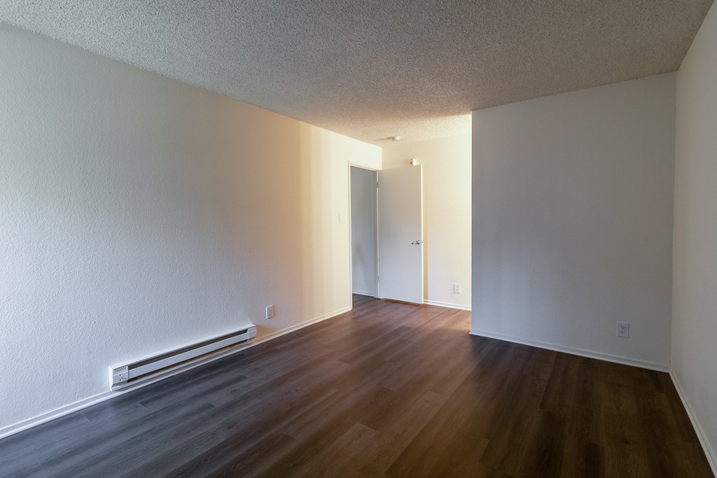 an empty living room with wood floors and white walls