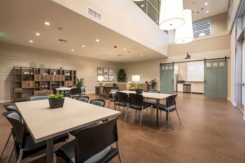 a dining room with tables and chairs and a kitchen