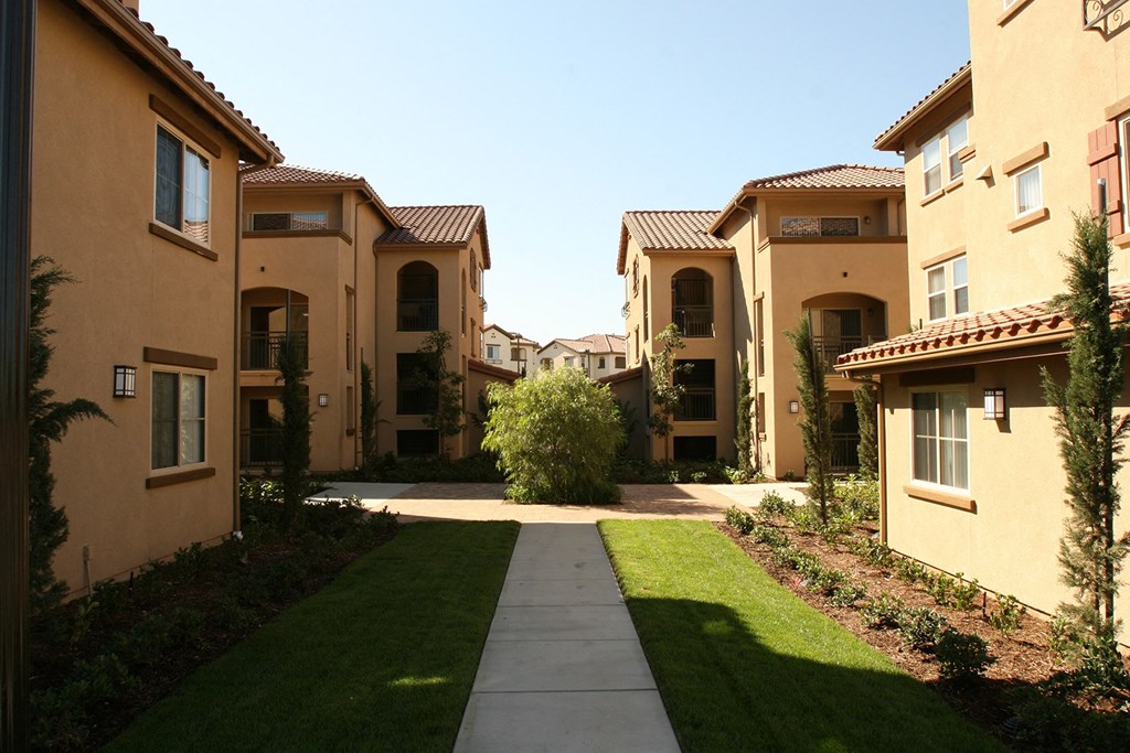 a group of apartments with grass and a sidewalk