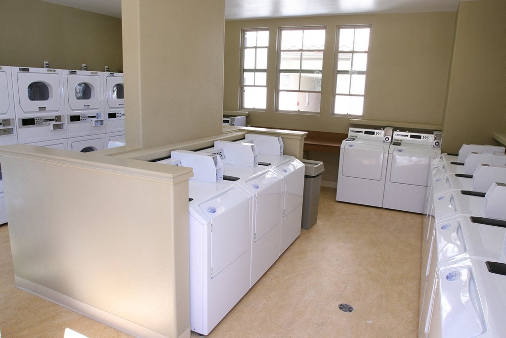 a room filled with washers and dryers in a large room with windows