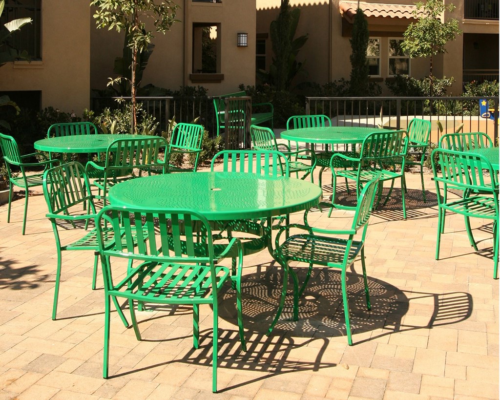 a group of green tables and chairs in a courtyard