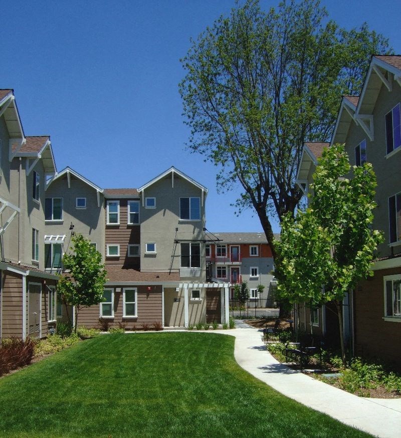 a view of a row of apartments with grass and trees