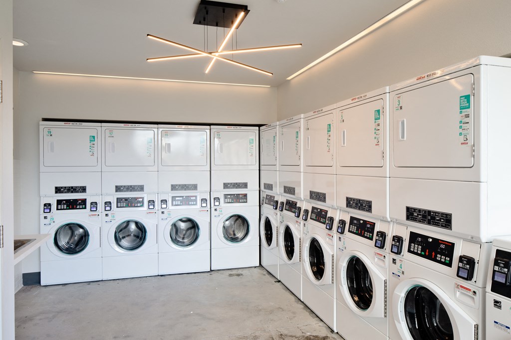 a row of washing machines and dryers in a laundry room
