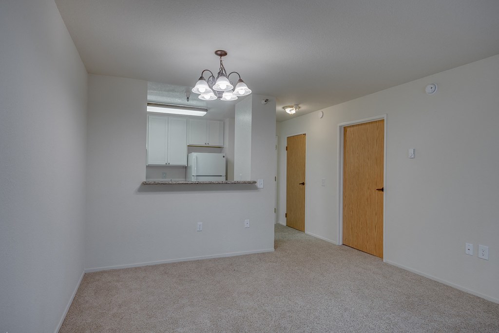 an empty living room with a door to the kitchen