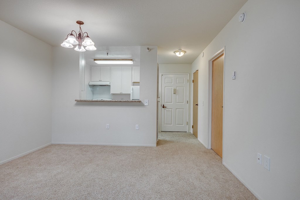 a spacious living room with carpet and a door to the bathroom