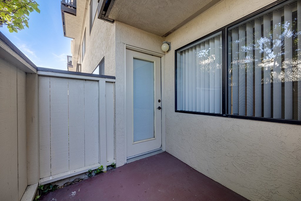 a patio with a white fence and a door to a balcony