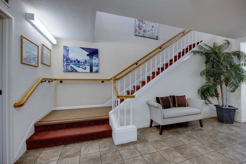 the landing of a staircase in a home with a chair and a plant