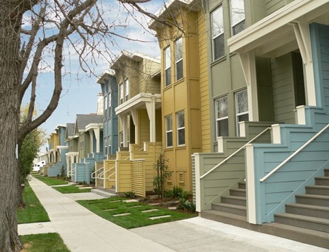 a row of yellow and blue houses on a sidewalk