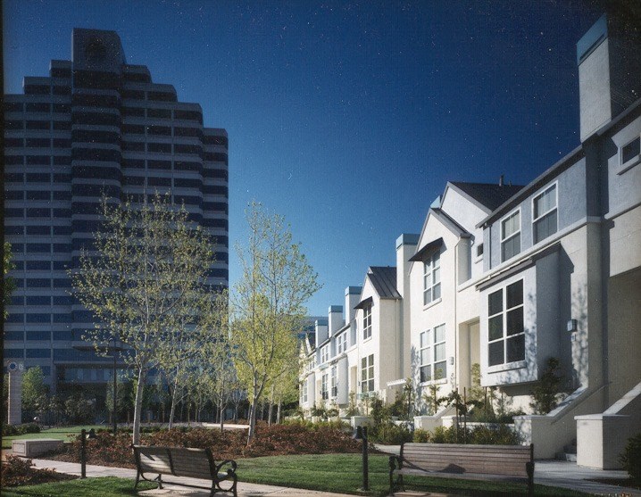 a row of houses with trees and benches in front of a tall building