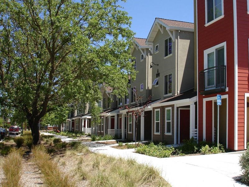 a row of houses with trees and a sidewalk