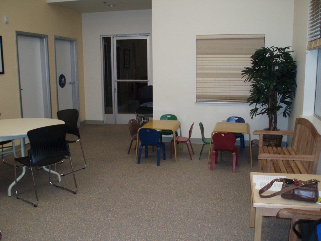 a waiting room with tables and chairs and a plant