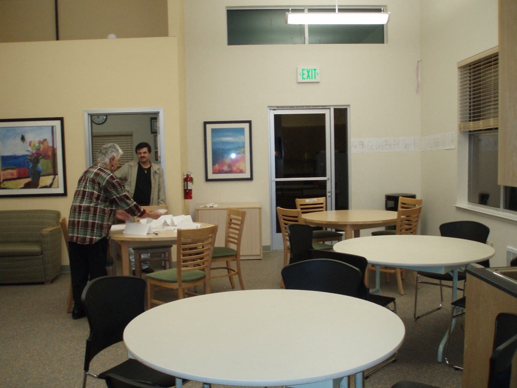 a man standing at a table in a room with tables and chairs