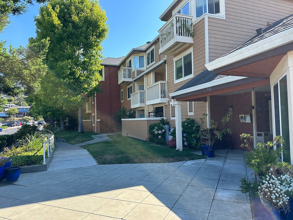 an empty sidewalk in front of an apartment building