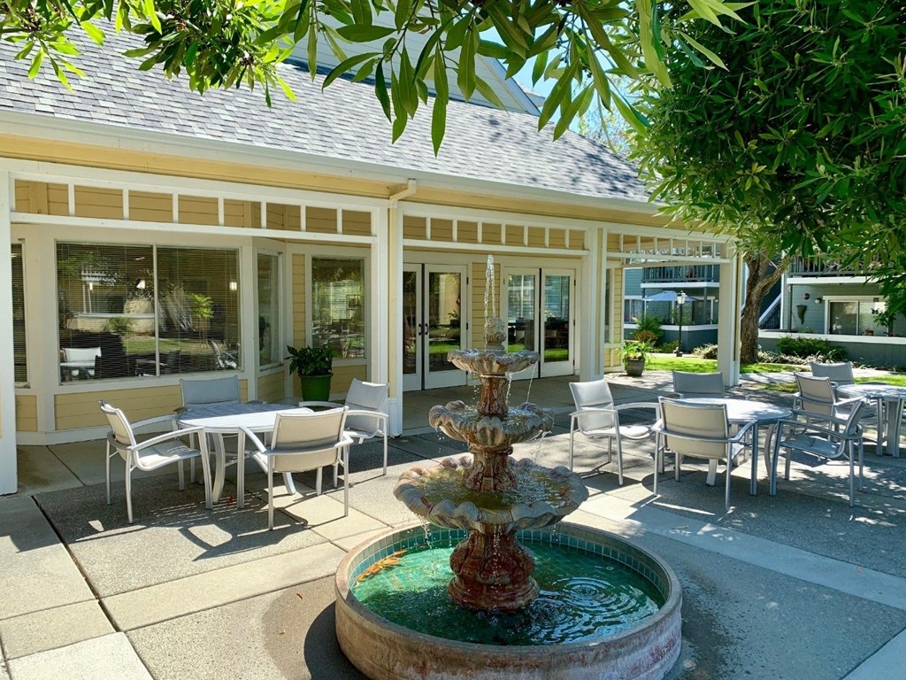 a fountain in the courtyard of a restaurant with tables and chairs