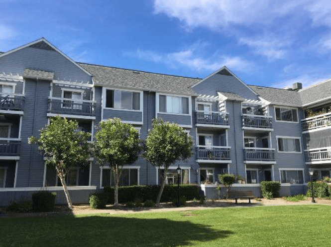 an apartment building with four trees in front of it