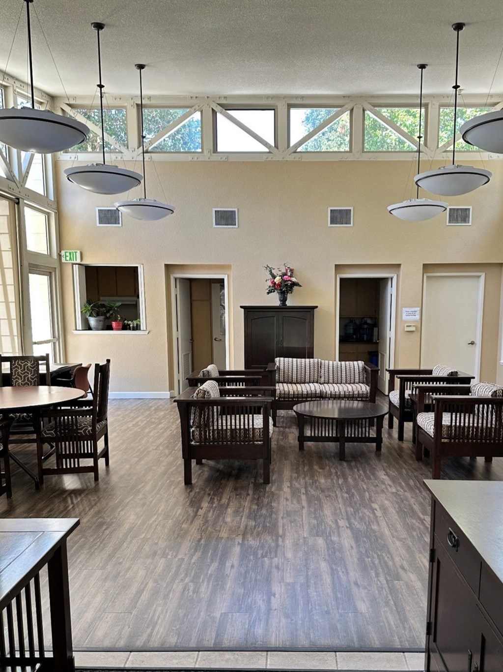 a large living room with tables and chairs and windows