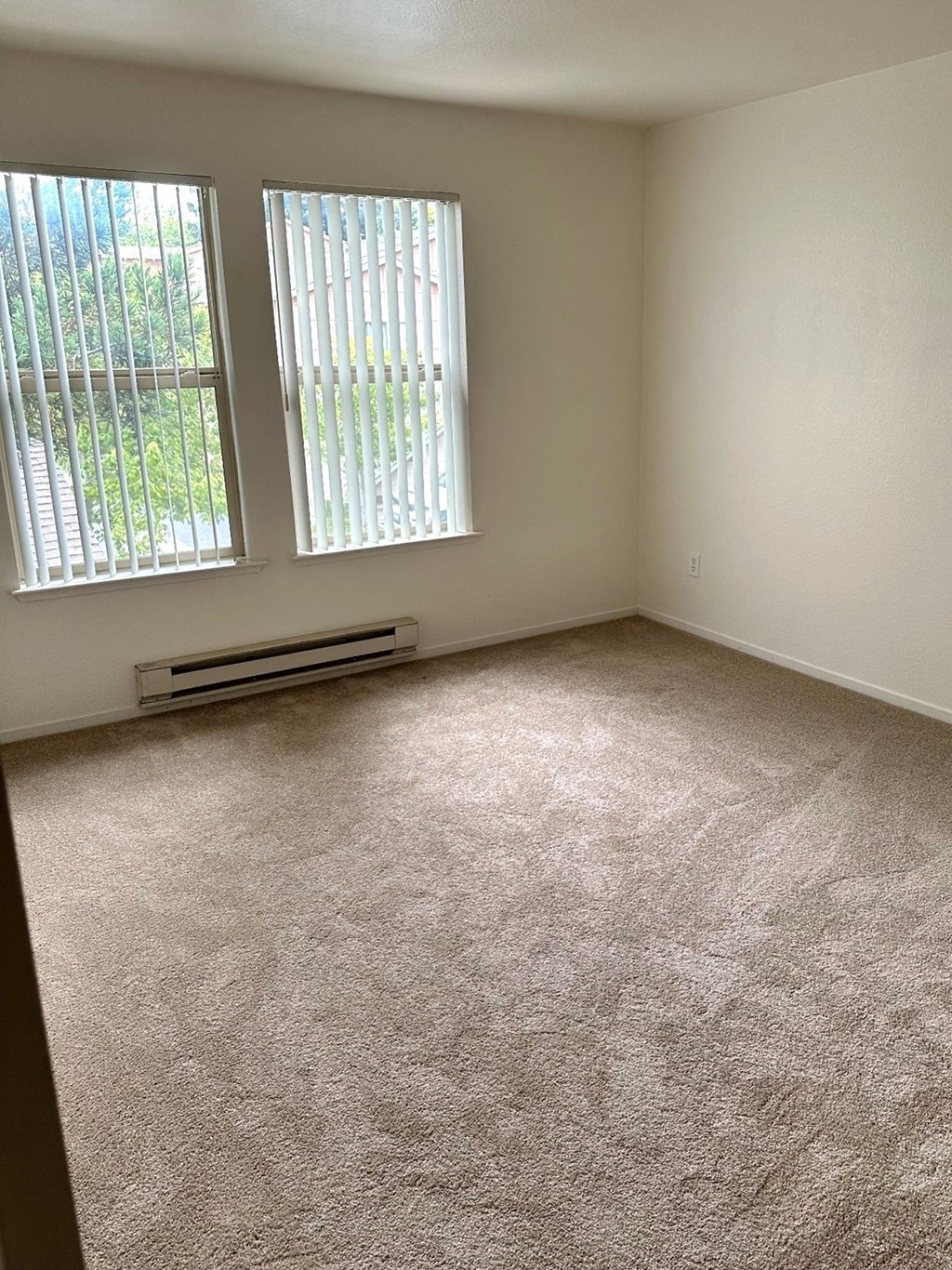 an empty room with carpet and two windows