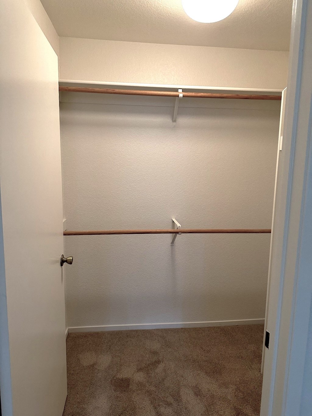 a walk in closet with a white wall and a closet door