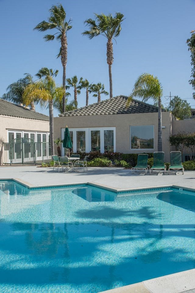 a large swimming pool in front of a house with palm trees