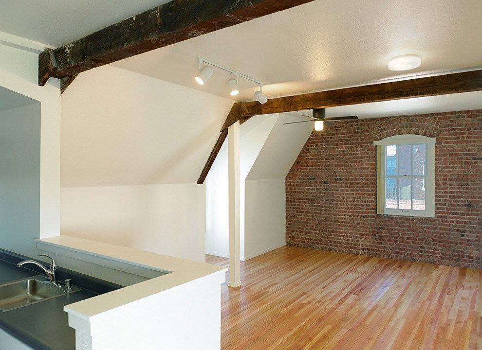 a living room with a brick wall and wood floors