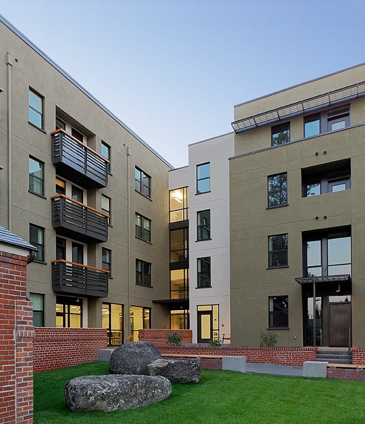 a group of modern apartment buildings with grass and rocks