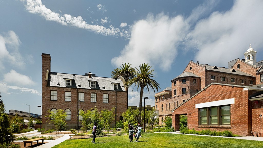 a group of people walking on a lawn in front of buildings