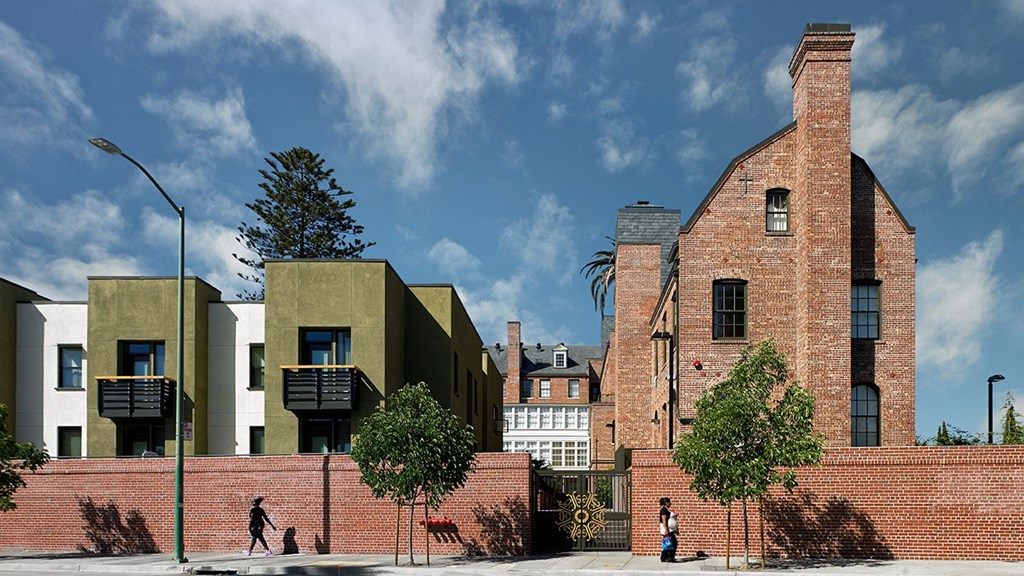 a red brick wall in front of a brick building and a group of modern buildings