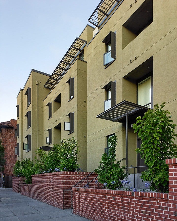 a row of apartment buildings with bricks and plants