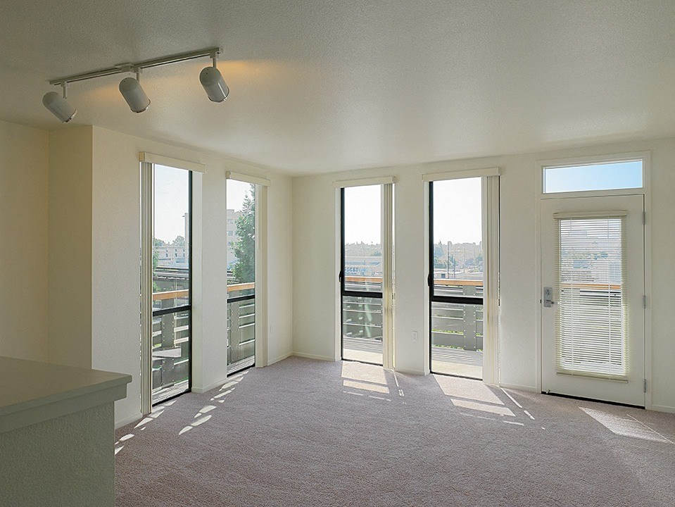 an empty living room with windows and a balcony