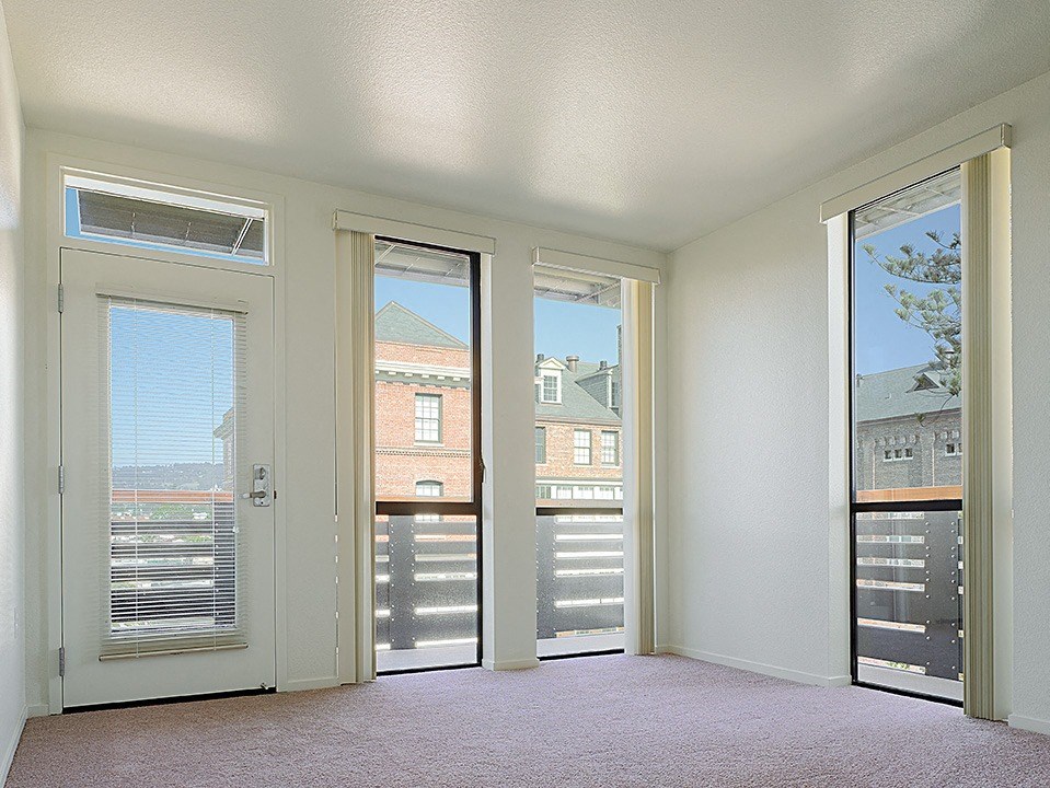 an empty living room with three windows and a door