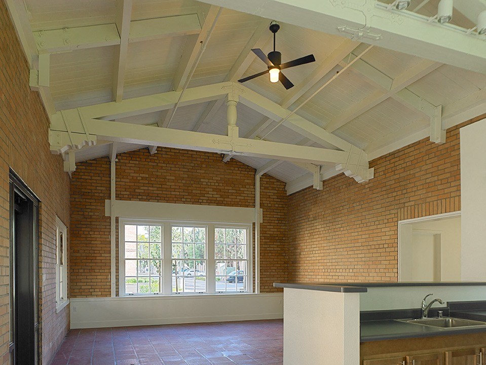 an empty room with a brick wall and a ceiling fan