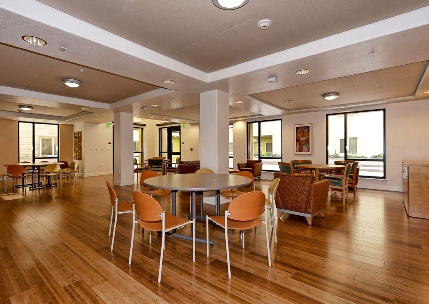 a room with tables and chairs in a large room with windows