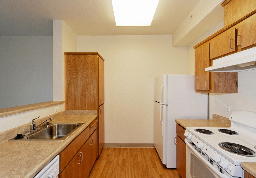 an empty kitchen with a stove refrigerator and sink