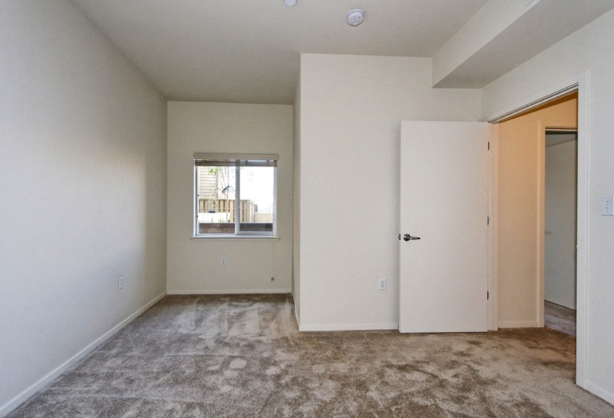 an empty living room with a door to a closet and a window