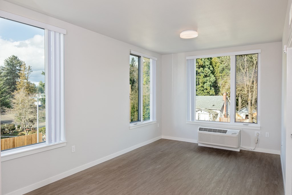 an empty living room with large windows and a radiator