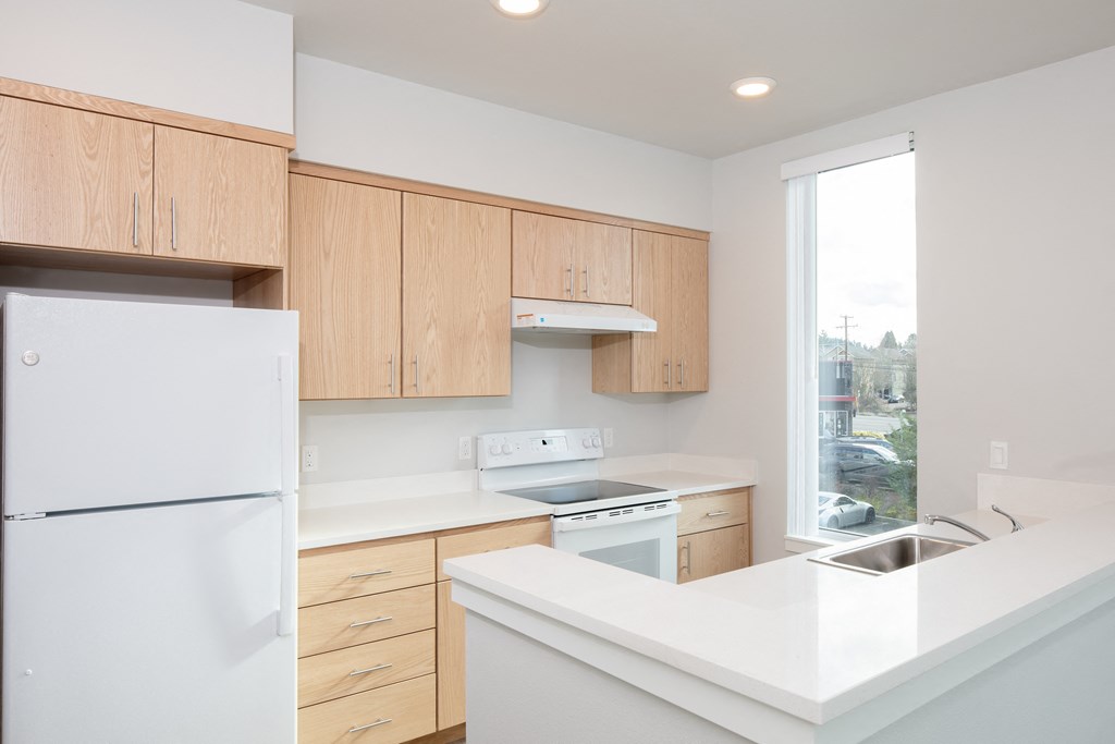 an empty kitchen with white counter tops and wooden cabinets