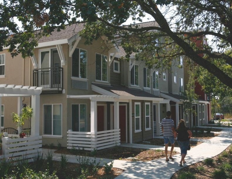 a man and a woman walking down a sidewalk in front of houses